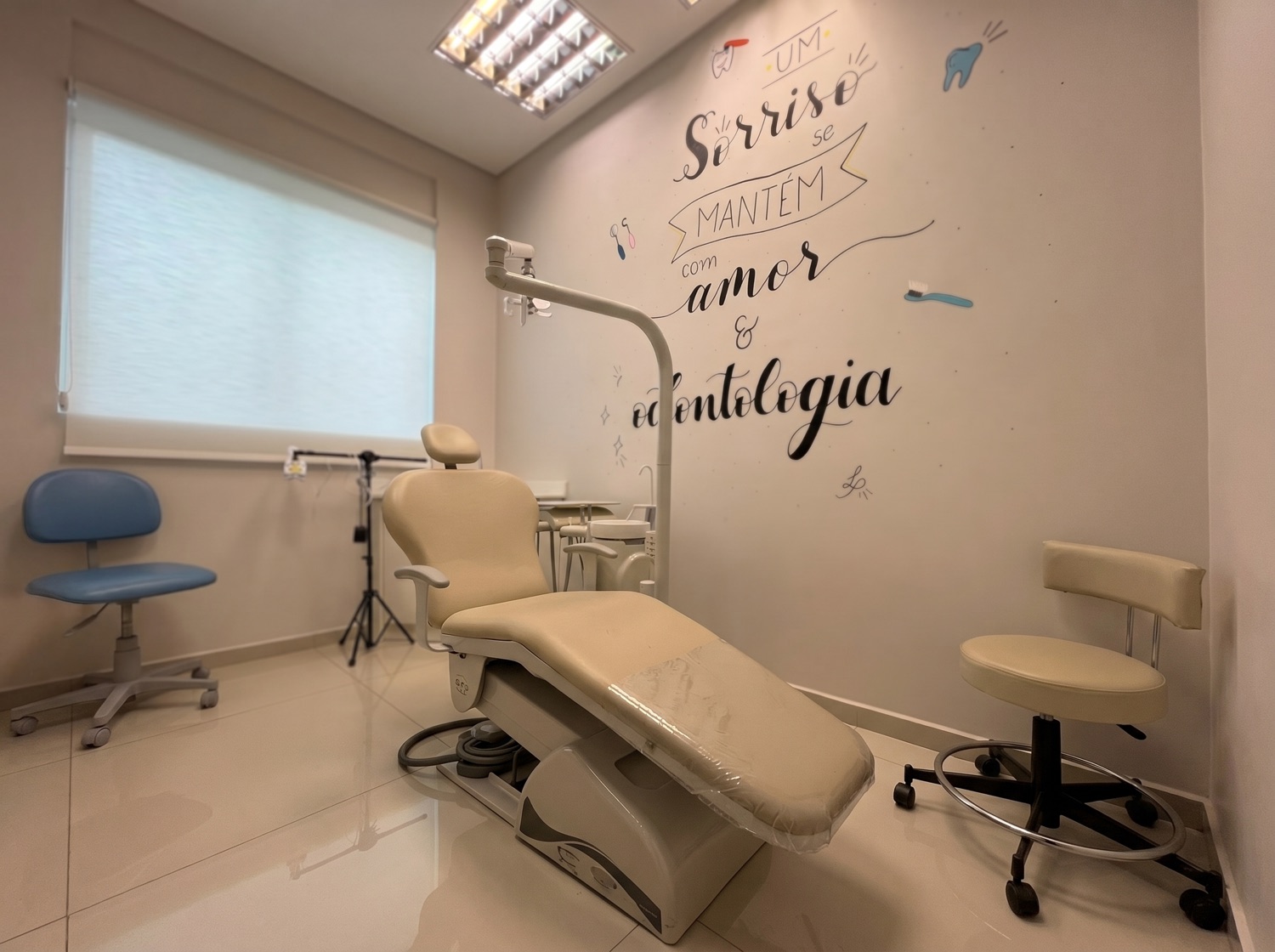 Sala de atendimento com a frase 'Um sorriso se mantém com amor e odontologia' na parede